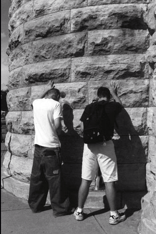 two men (acting if) urinating on a building